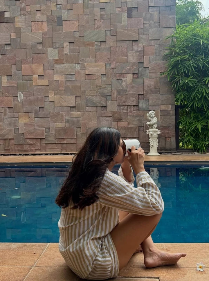 Person sitting by a pool, taking a photo with a smartphone.