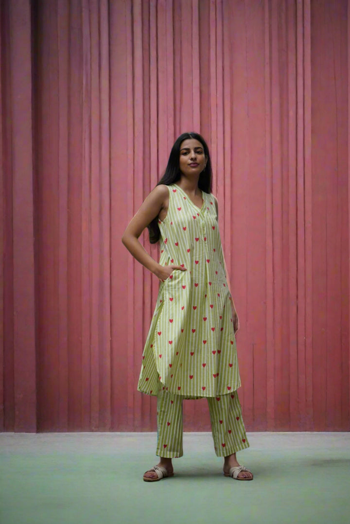 Woman in a green dress standing in front of a metal gate and red wall.